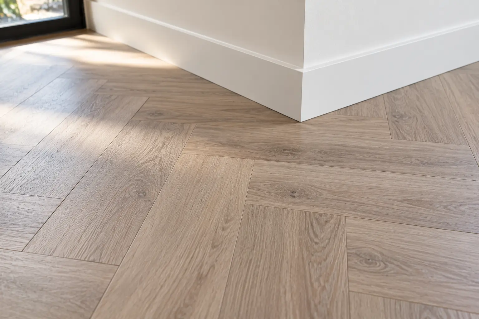 Close-up van een pvc-vloer in visgraat die aansluit op een witte plint